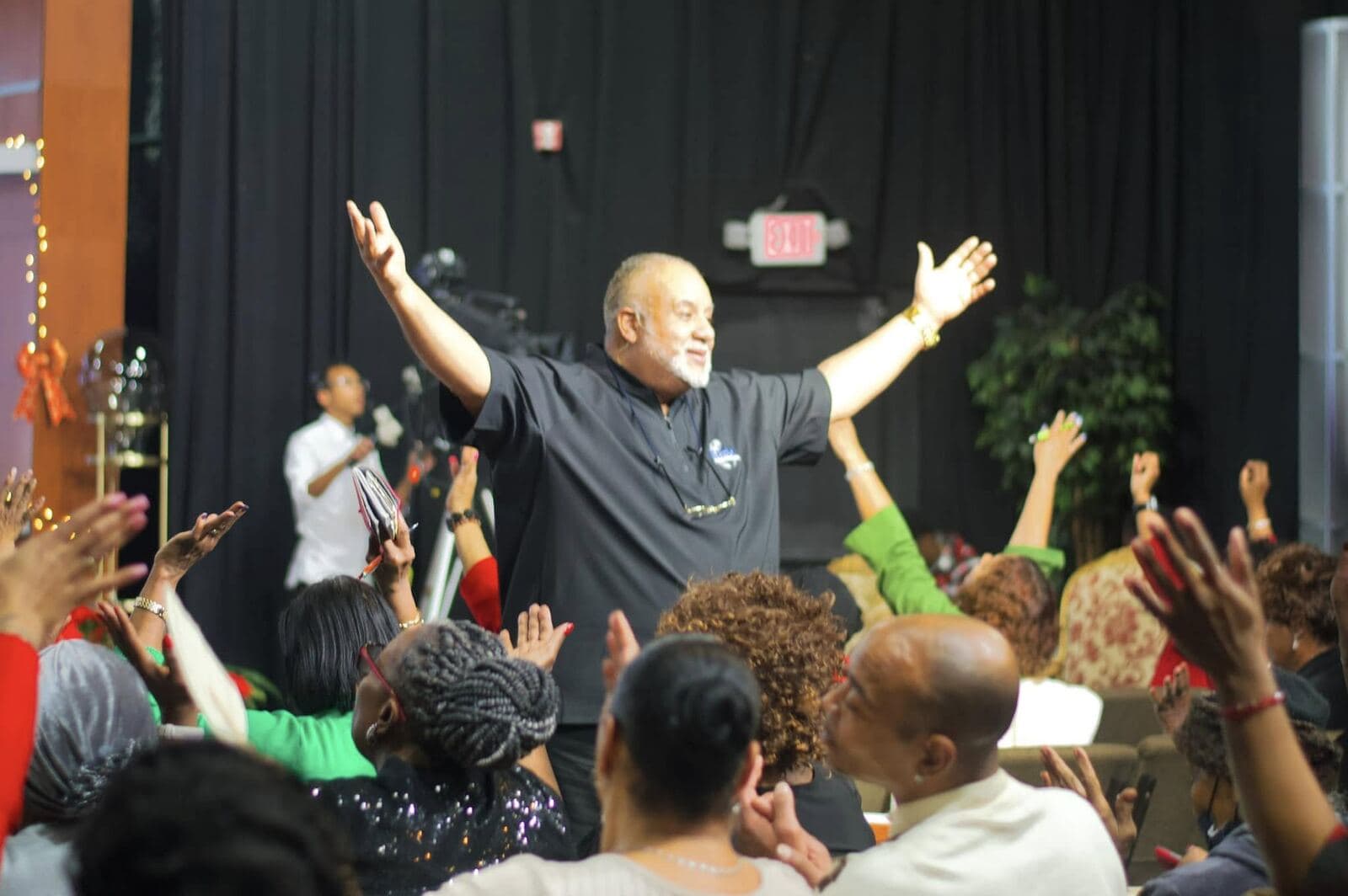 The NGBM congregation with hands raised in worship