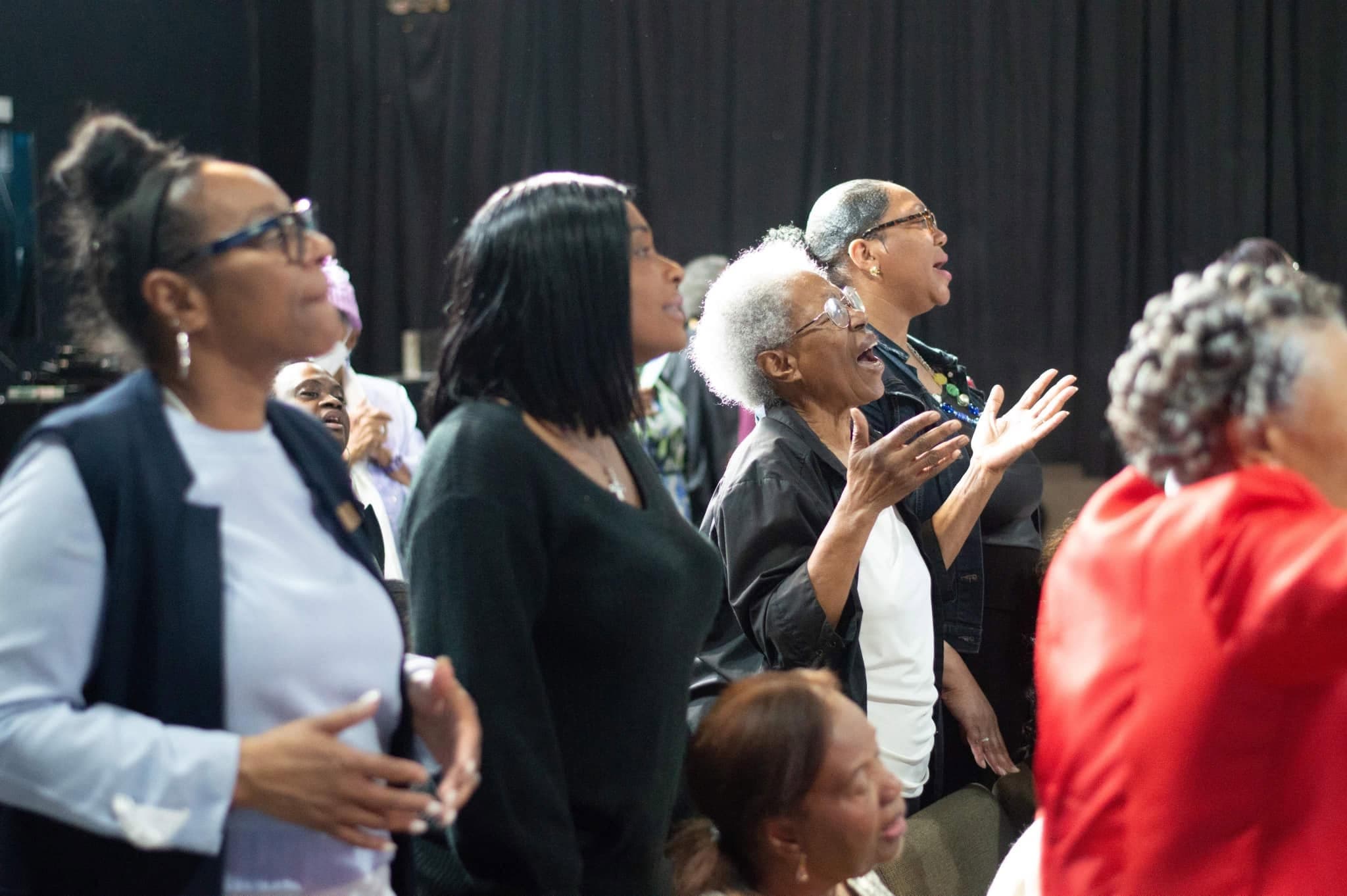 NGBM congregation worshipping with hands raised
